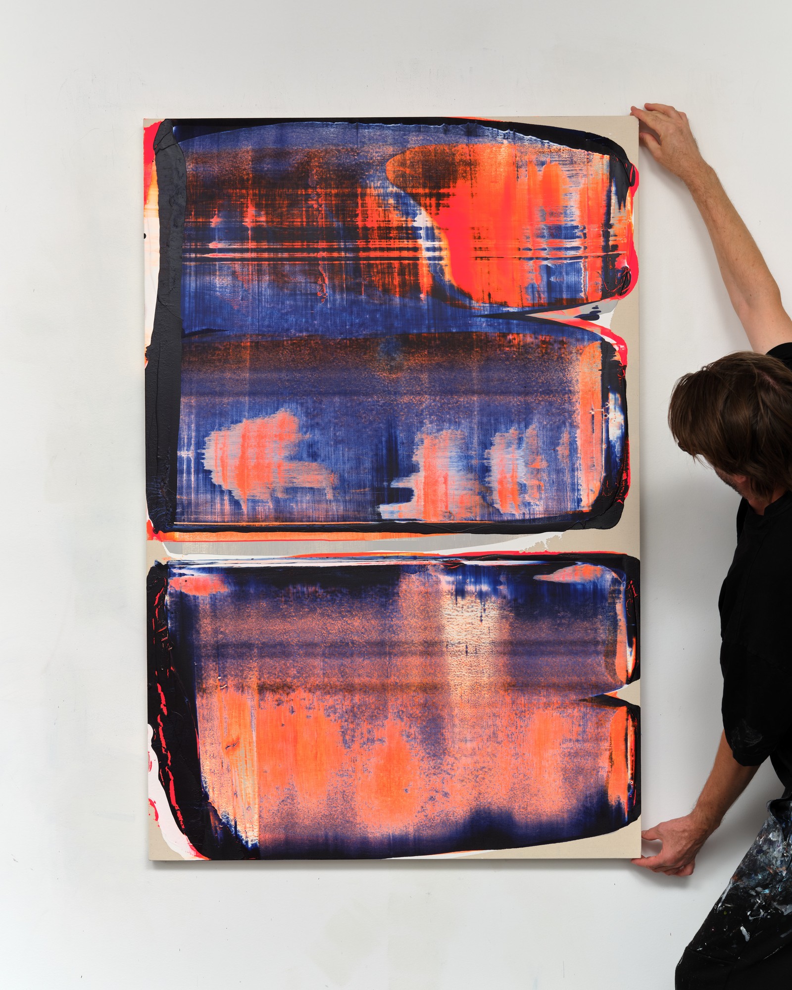 Alex Kuznetsov holding an orange and blue painting in the studio