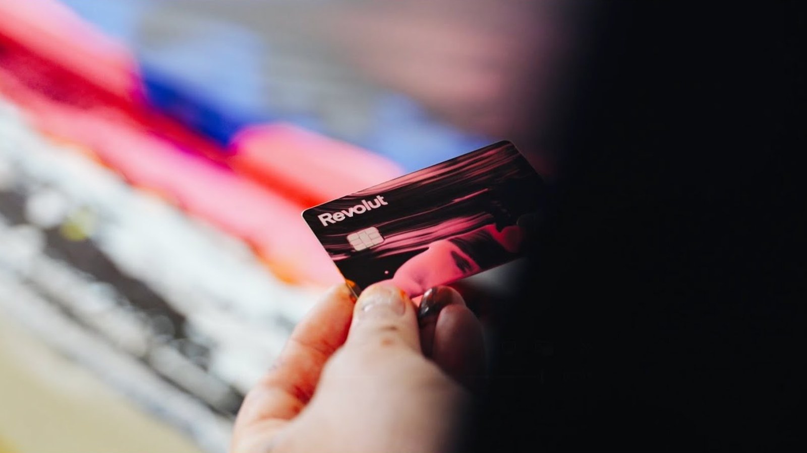 Une carte Revolut de la collection The Art of Payments devant une peinture d’Alex Kuznetsov, image du film Revolut